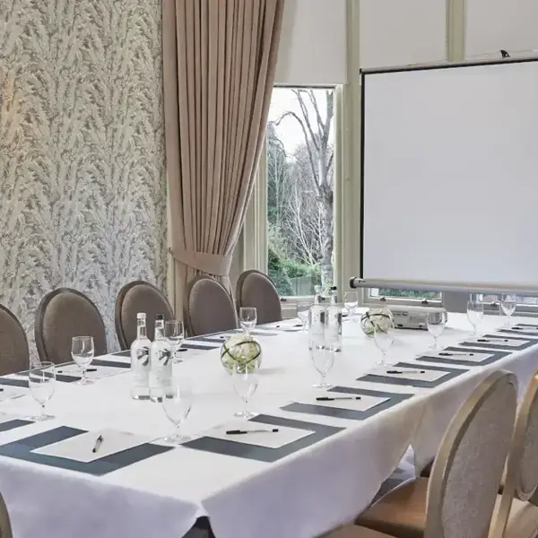 Ardberg room with a long and furnished table and a projector screen