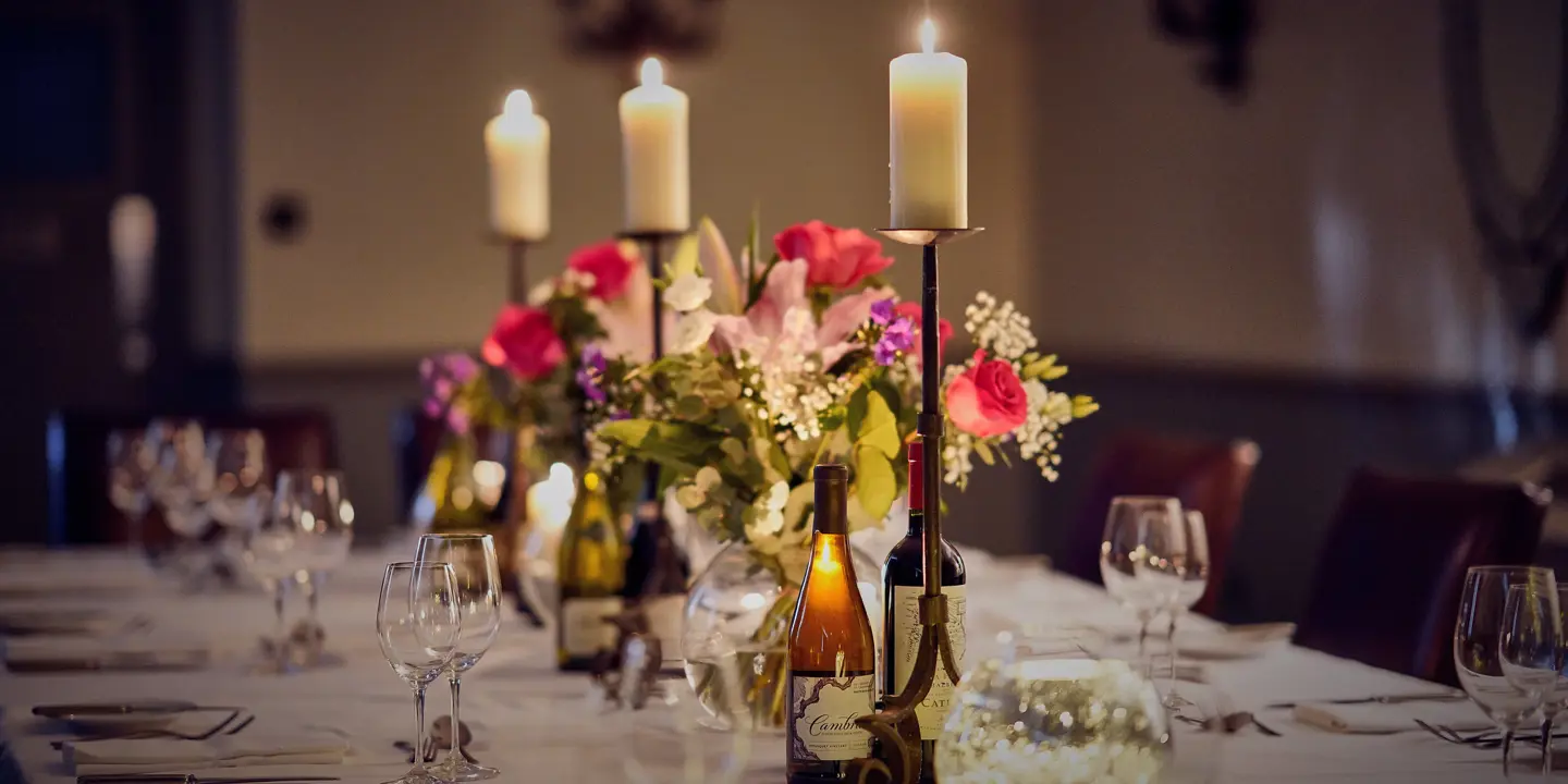 A table adorned with wine bottles and flickering candles.