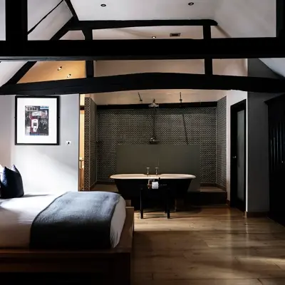 High ceiling room with wooden beams, a bed and large bathtub