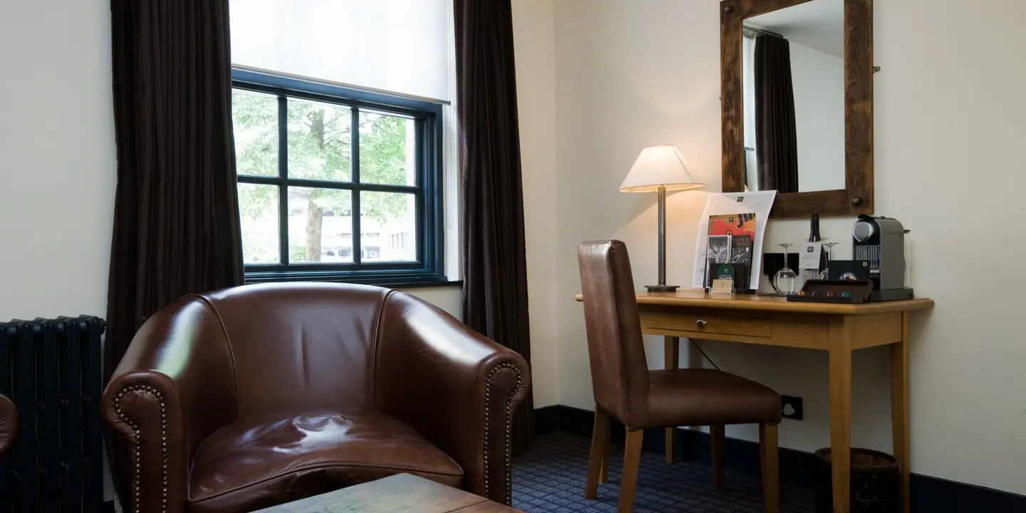 An elegantly furnished hotel room featuring a spacious desk and comfortable chair.