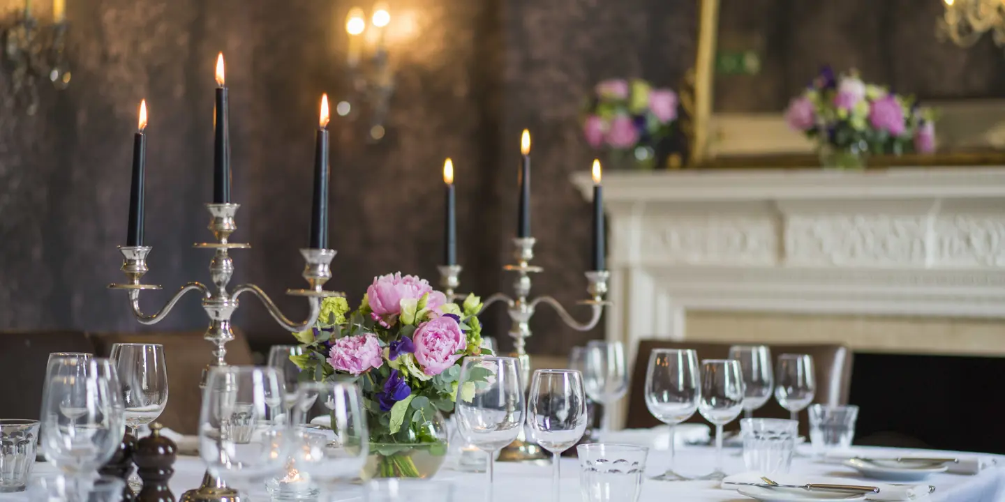 Table set for a formal dinner with candles and flowers.