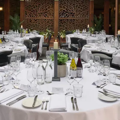 A table situated outside, adorned with pristine white tablecloths and elegantly arranged place settings.