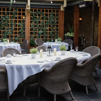 A table situated outside, adorned with pristine white tablecloths and elegantly arranged place settings.