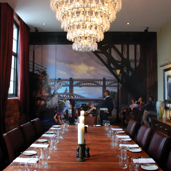 A dining room featuring a lengthy table adorned with an elegant chandelier.