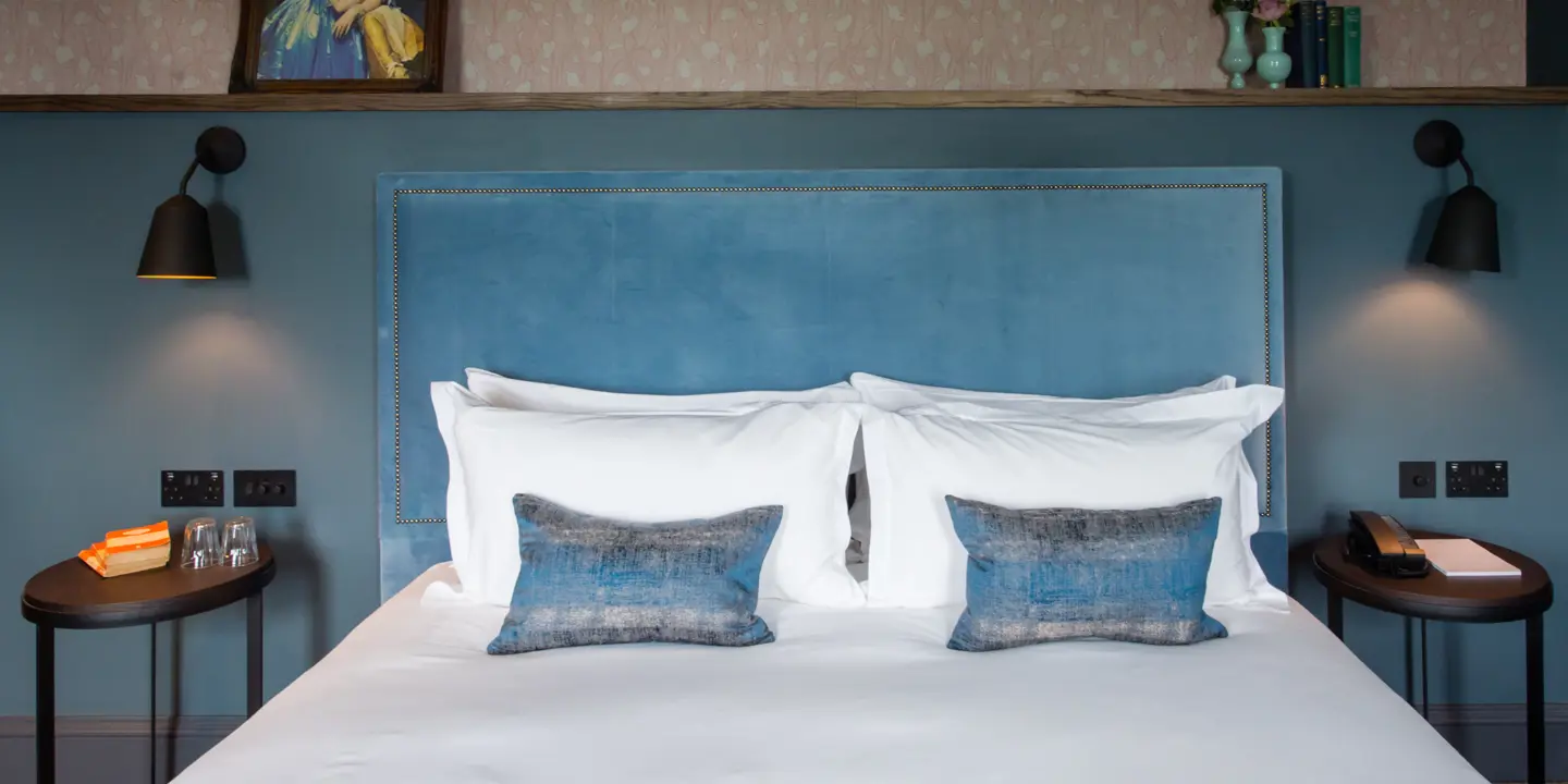 A bed featuring a stylish blue headboard and two comfortable pillows.