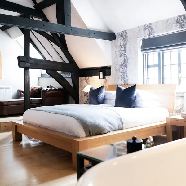 Bed in front of a window with dark wooden beams surrounding 