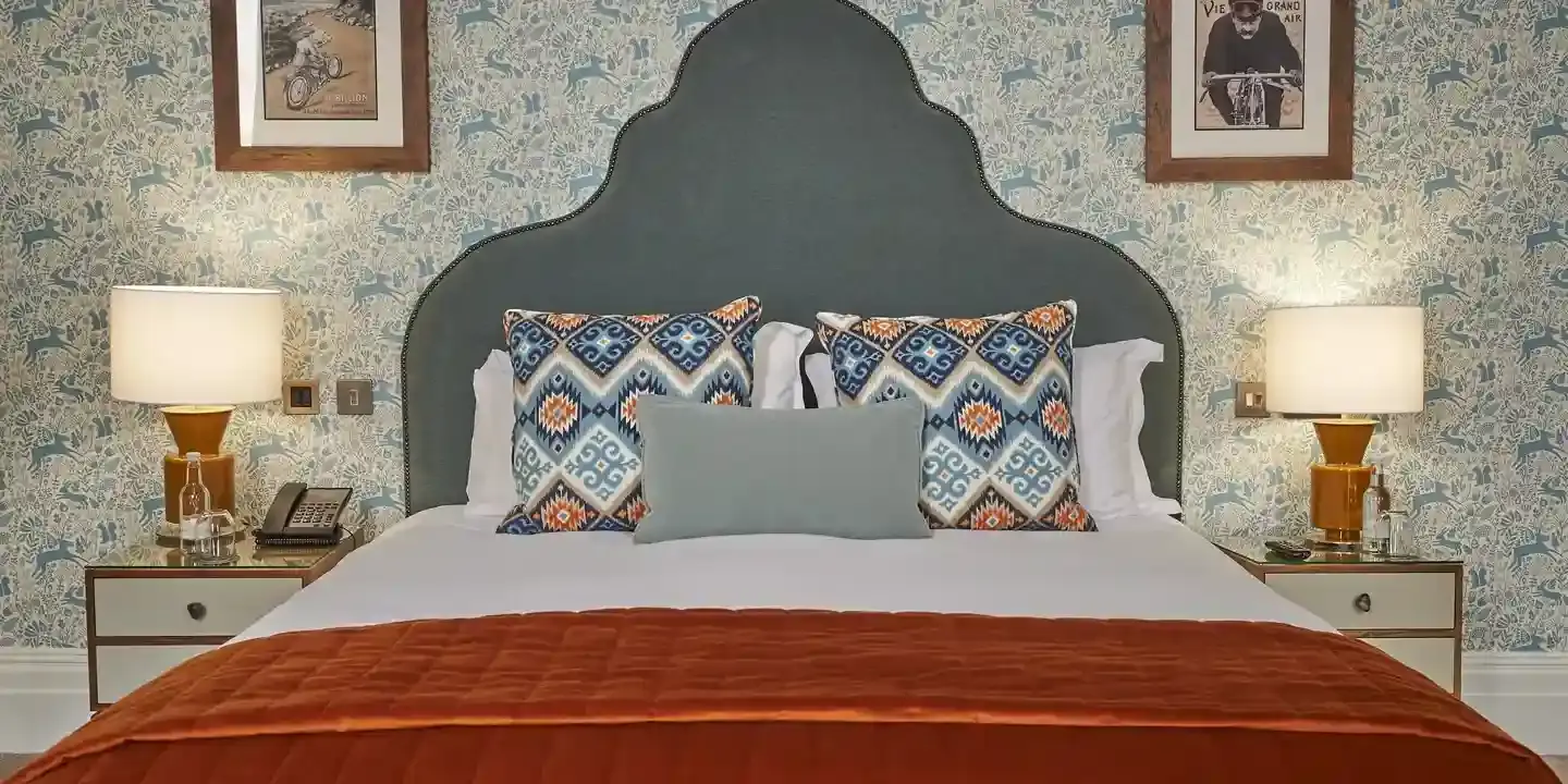 A bed with a headboard and two lamps on either side.