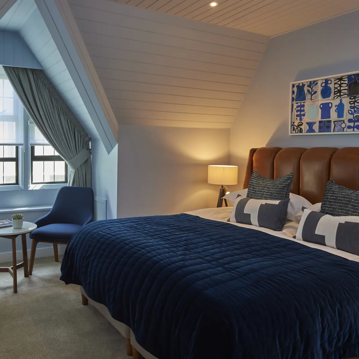 Spacious bedroom featuring a king-sized bed and an elegant chair.