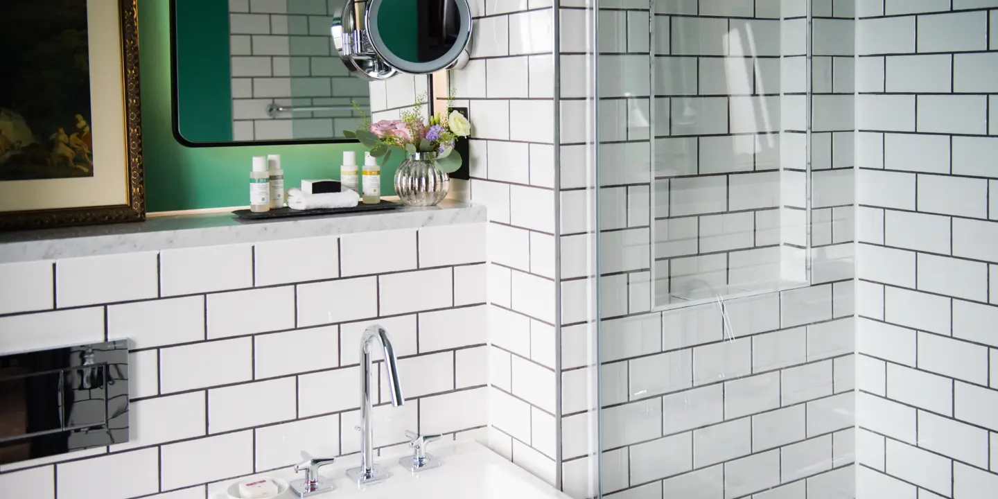A bathroom featuring a sink, mirror, and shower stall.