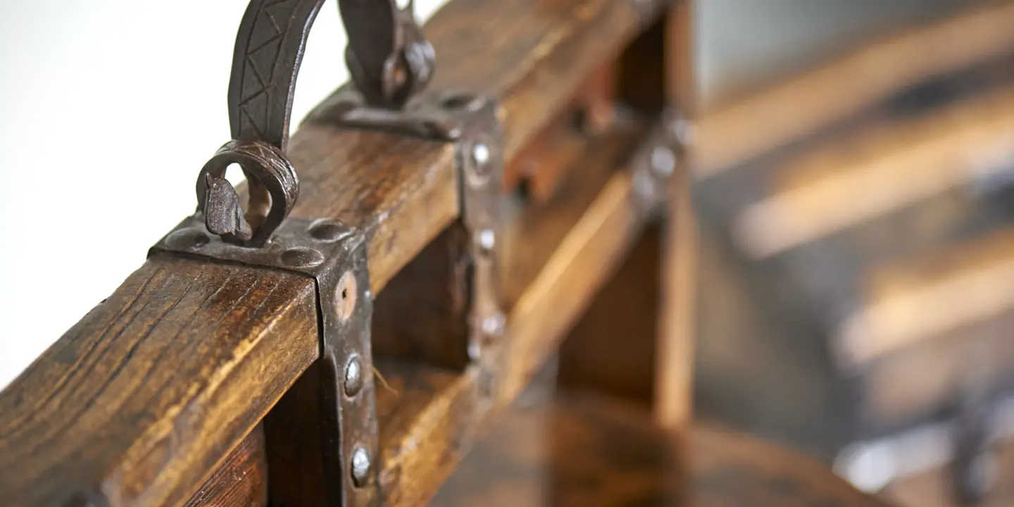 A detailed view of a wooden bench featuring metal hardware.