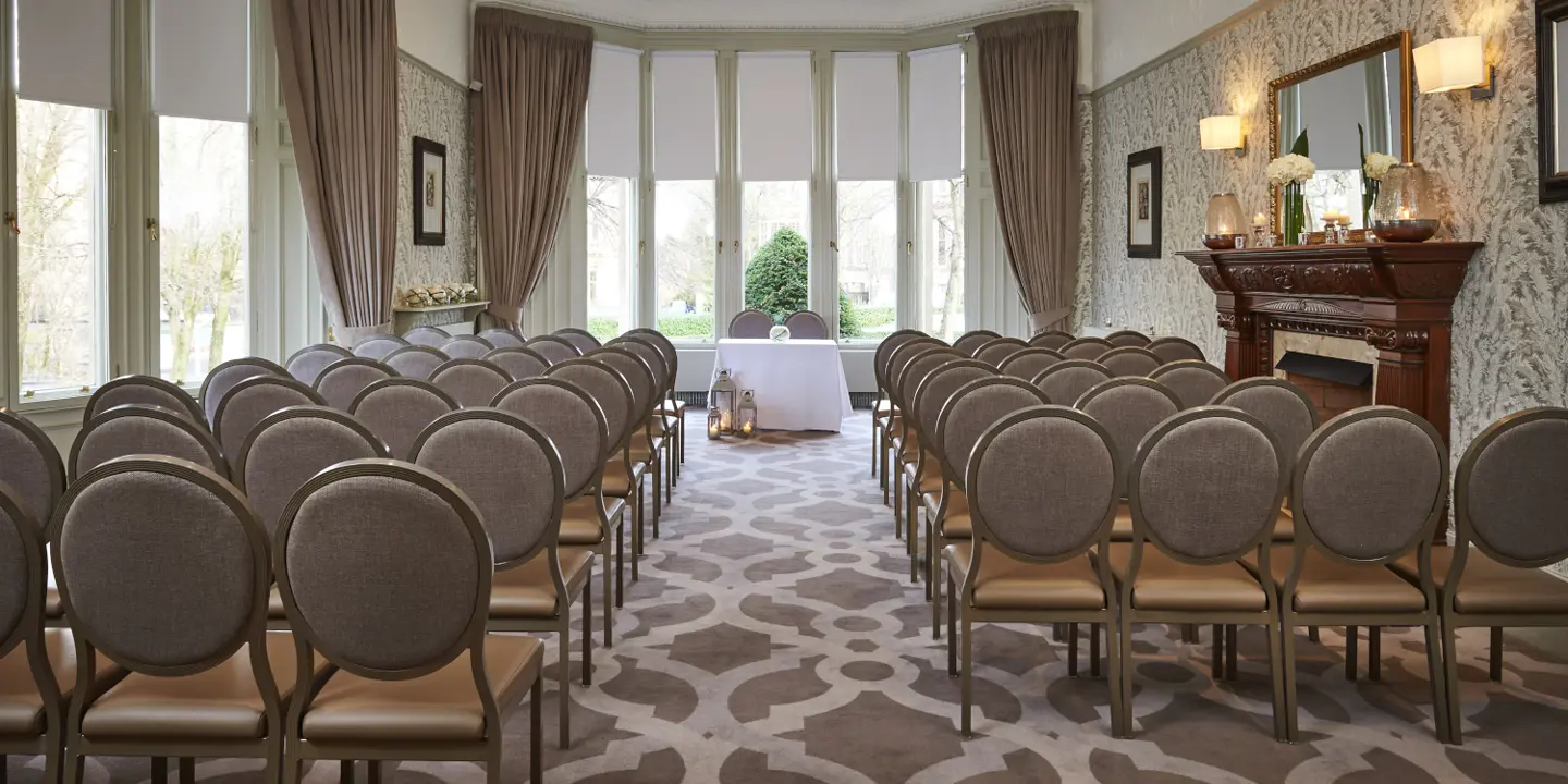 Spacious and well furnished room with two aisles with chairs featuring a fireplace