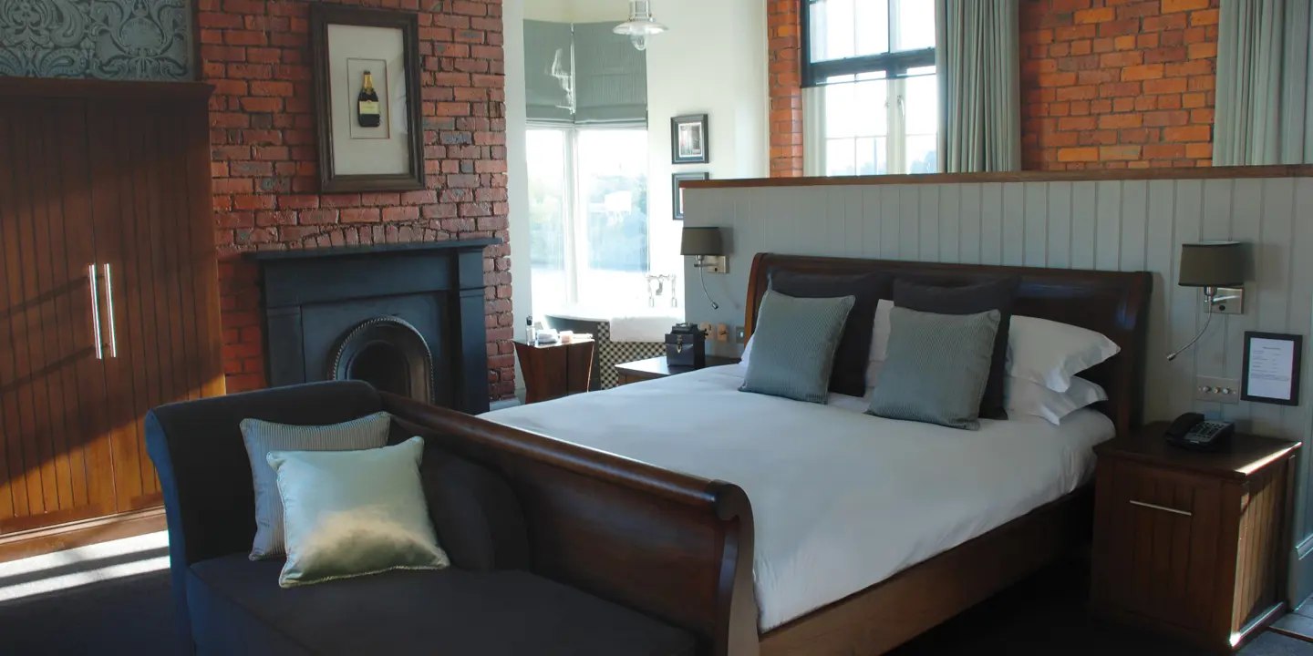 Bed positioned alongside a fireplace in a bedroom.