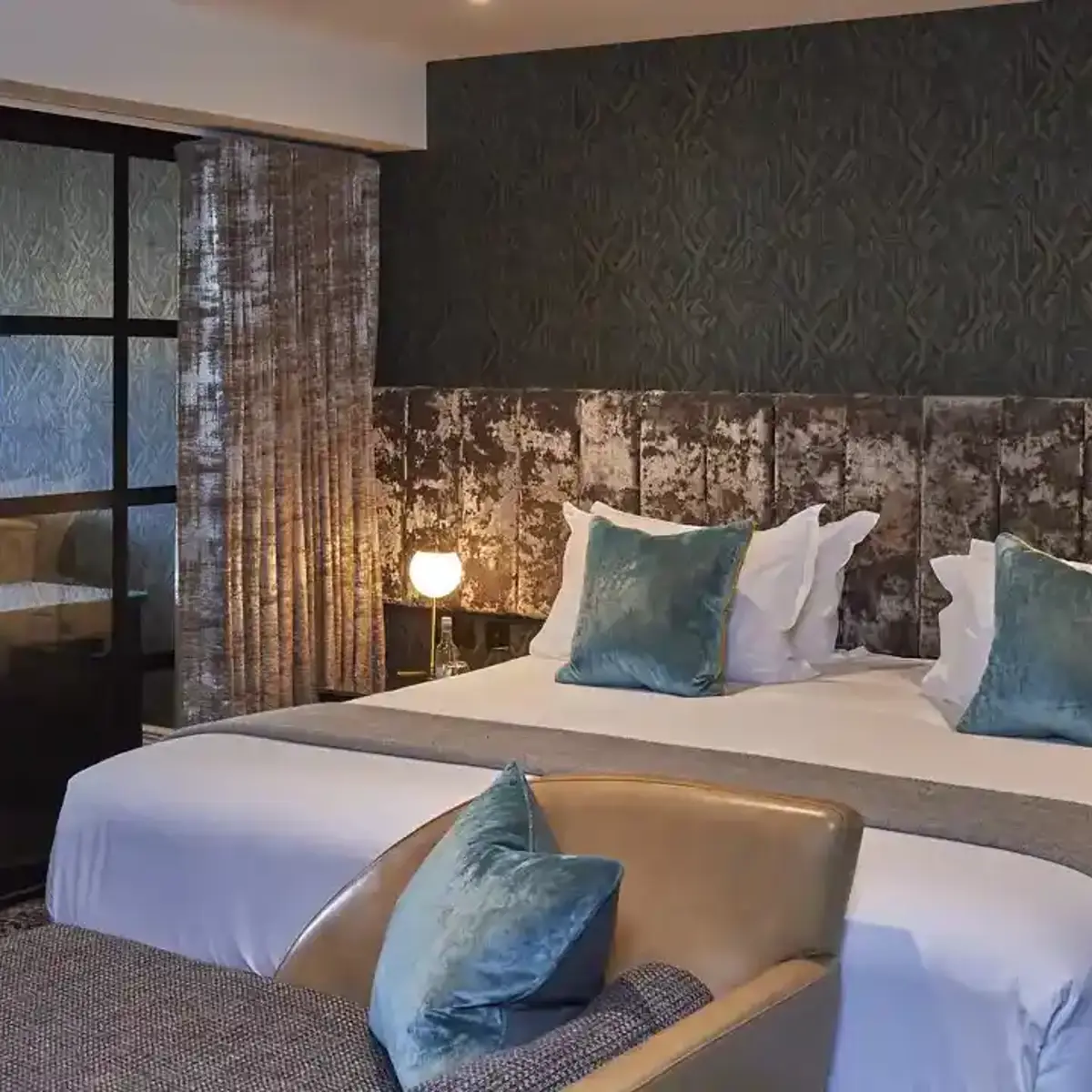 Spacious bedroom featuring a king-sized bed and an elegant chair.