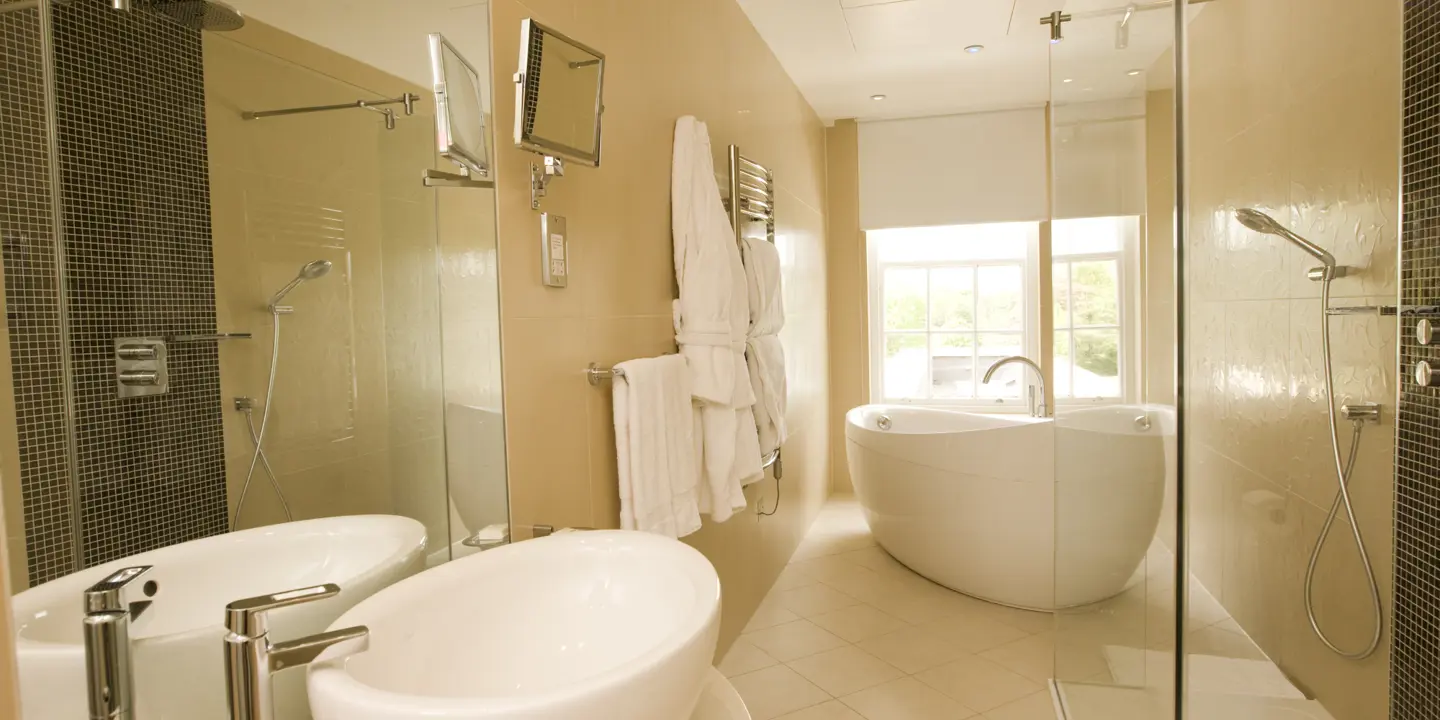 A bathroom featuring a sink, mirror, a bathtub and a dressing gown hanging on the wall.