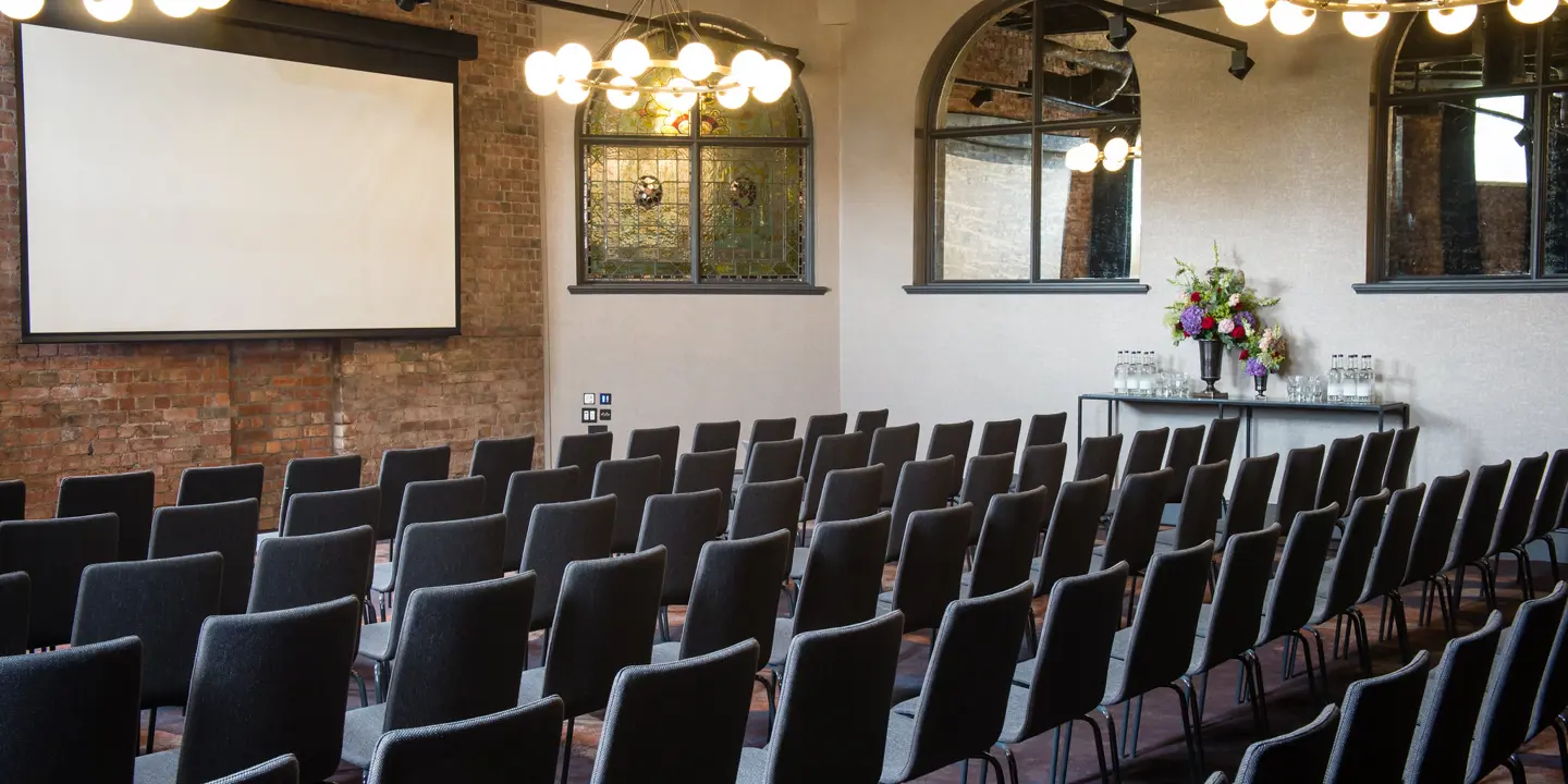 An auditorium with rows of chairs and a large projector screen.