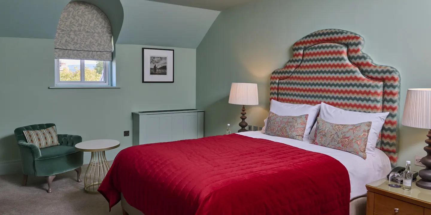 A bedroom decorated with neutral colours and bright red sheet on the bed