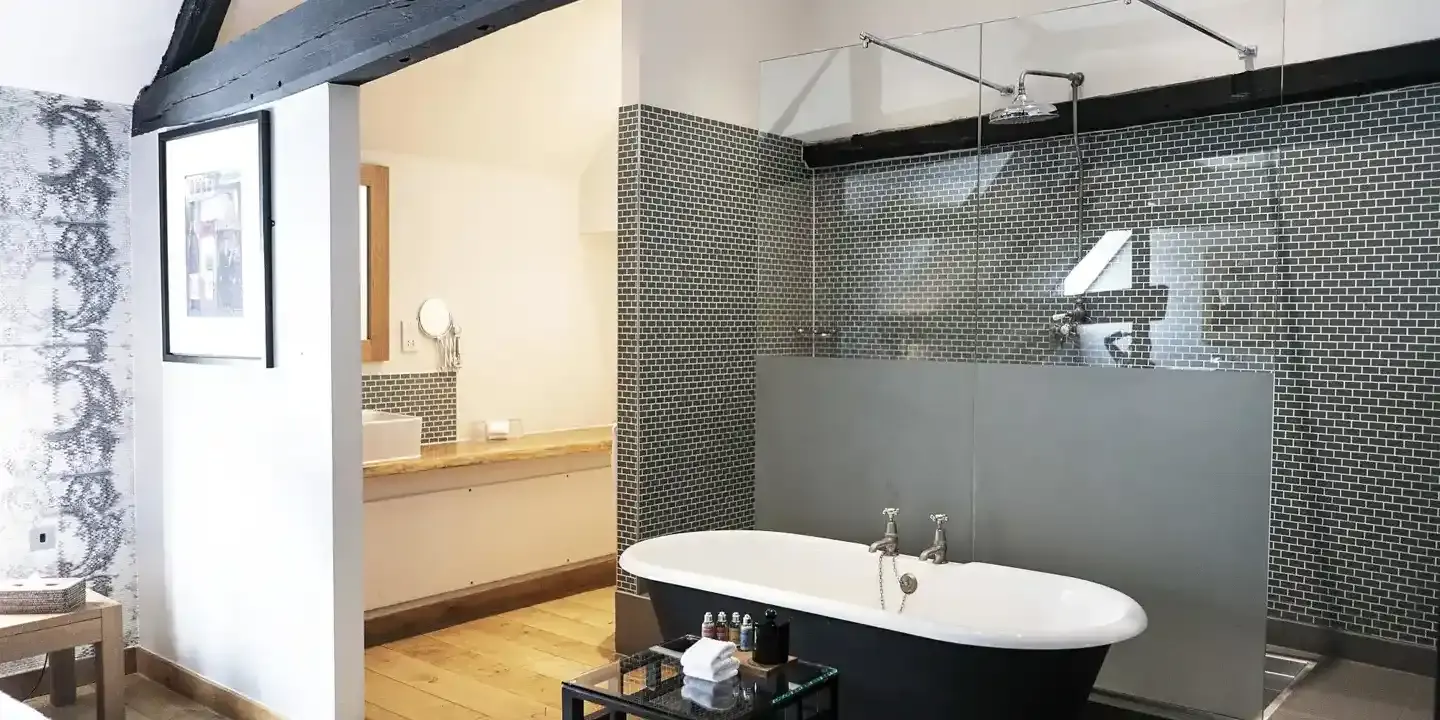 Bathtub in front of a large, black bricked tiled shower