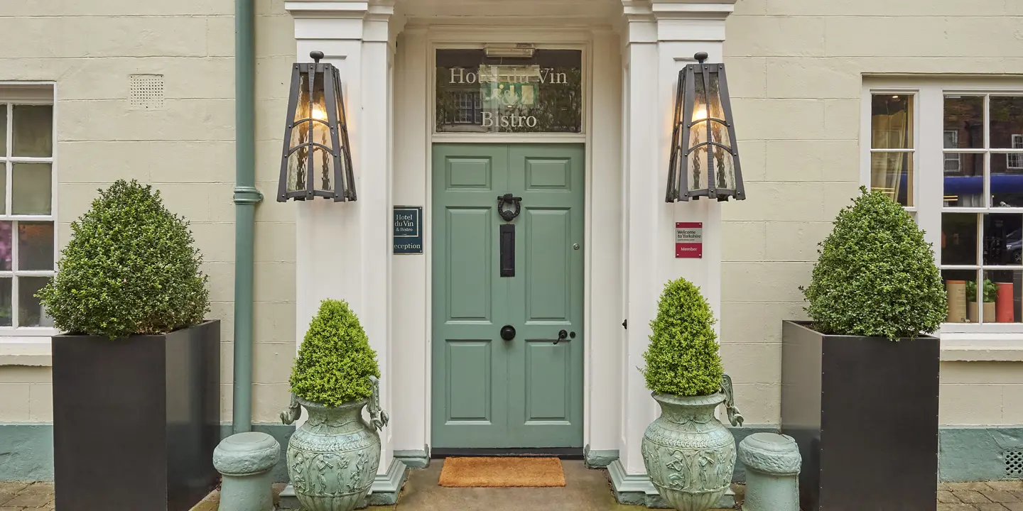 Entrance to a hotel featuring green door and four large planters