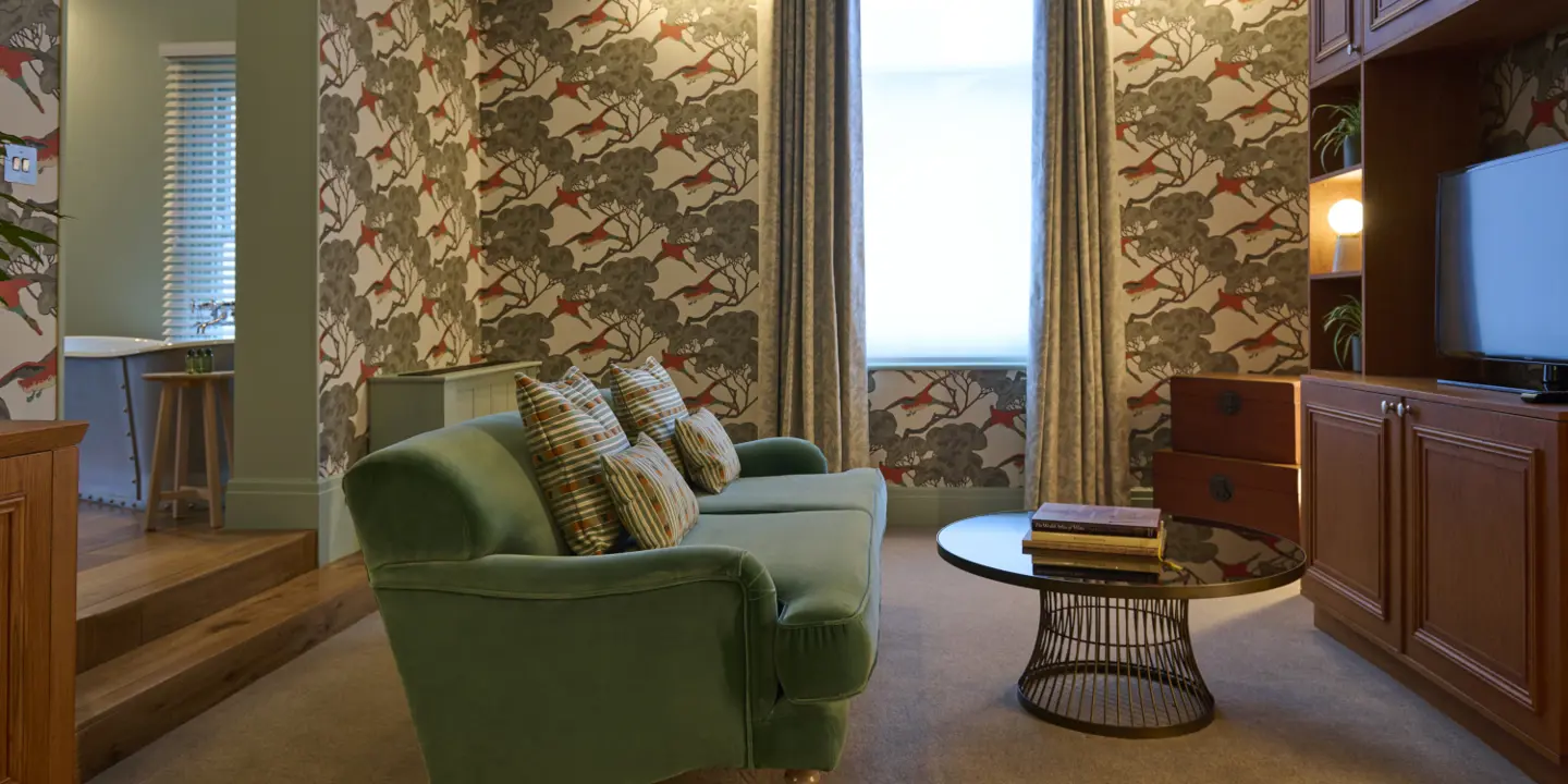 An earthy themed room decorated with a green sofa, a TV, and houseplants