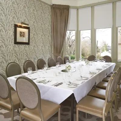 A dining room featuring a lengthy table adorned with an elegant glasses and paired with light brown chairs