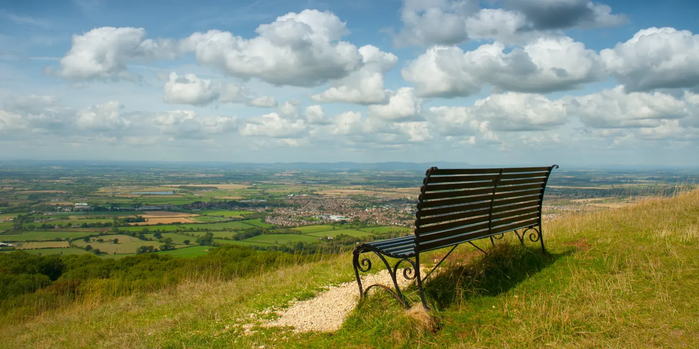 A wooden bench resting atop a verdant hillside.