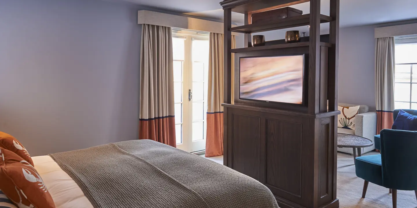 An elegantly furnished bedroom featuring a comfortable bed, a stylish chair, and a modern television.