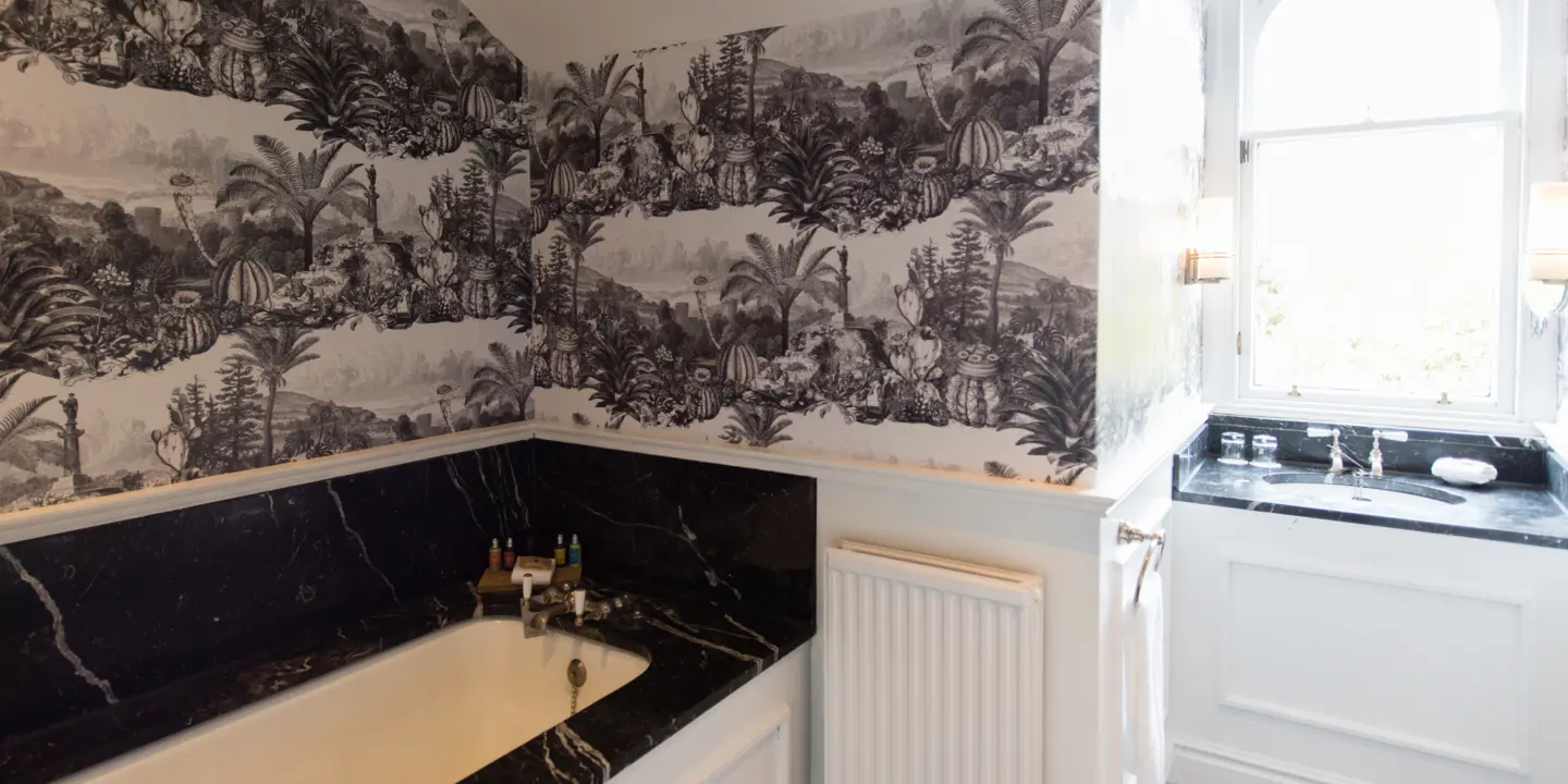 Black and white wallpapered bathroom with a bathtub