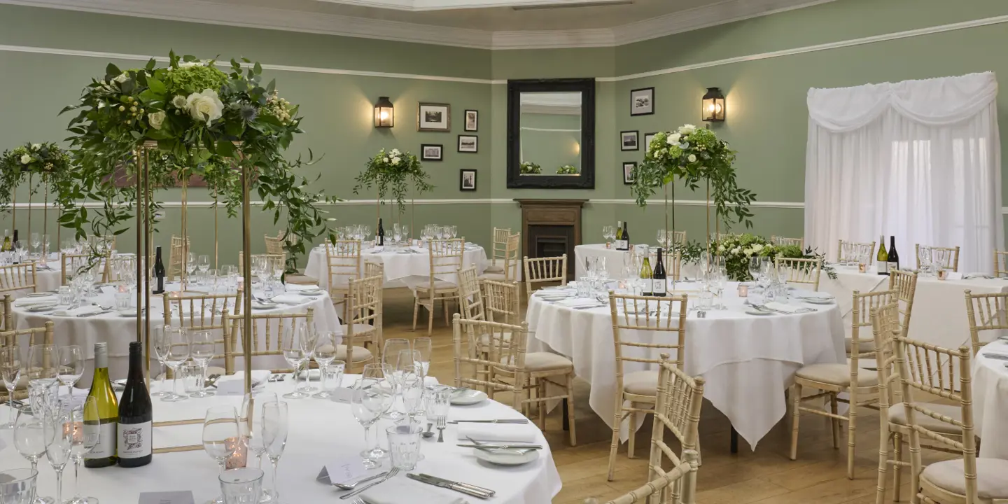 Round table adorned with white cloth, champagne glasses and flower arrangements.