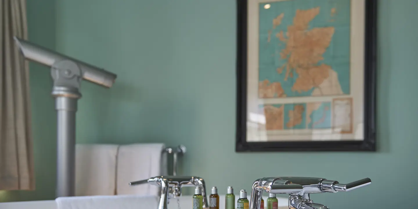 Bathroom sink featuring two faucets and a wall-mounted map.