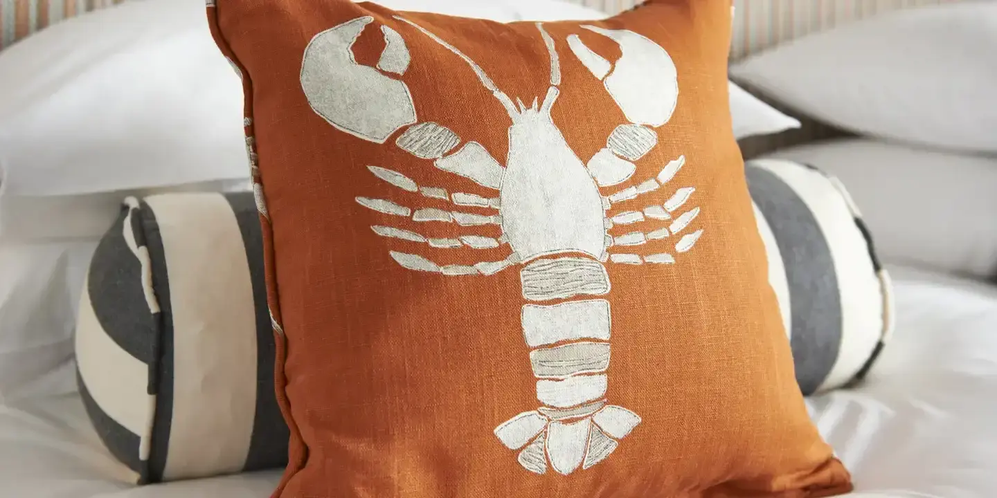 Lobster-themed pillow resting on a bed.