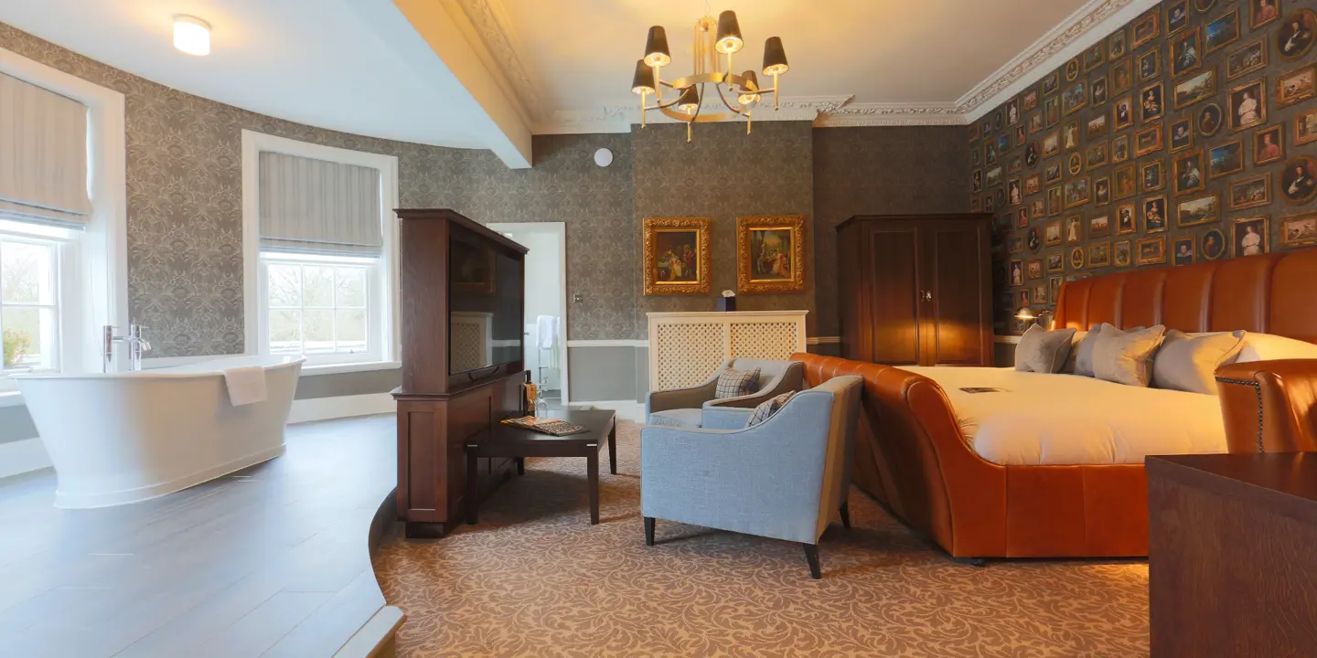 Spacious bedroom featuring a king-sized bed and an elegant bathtub.