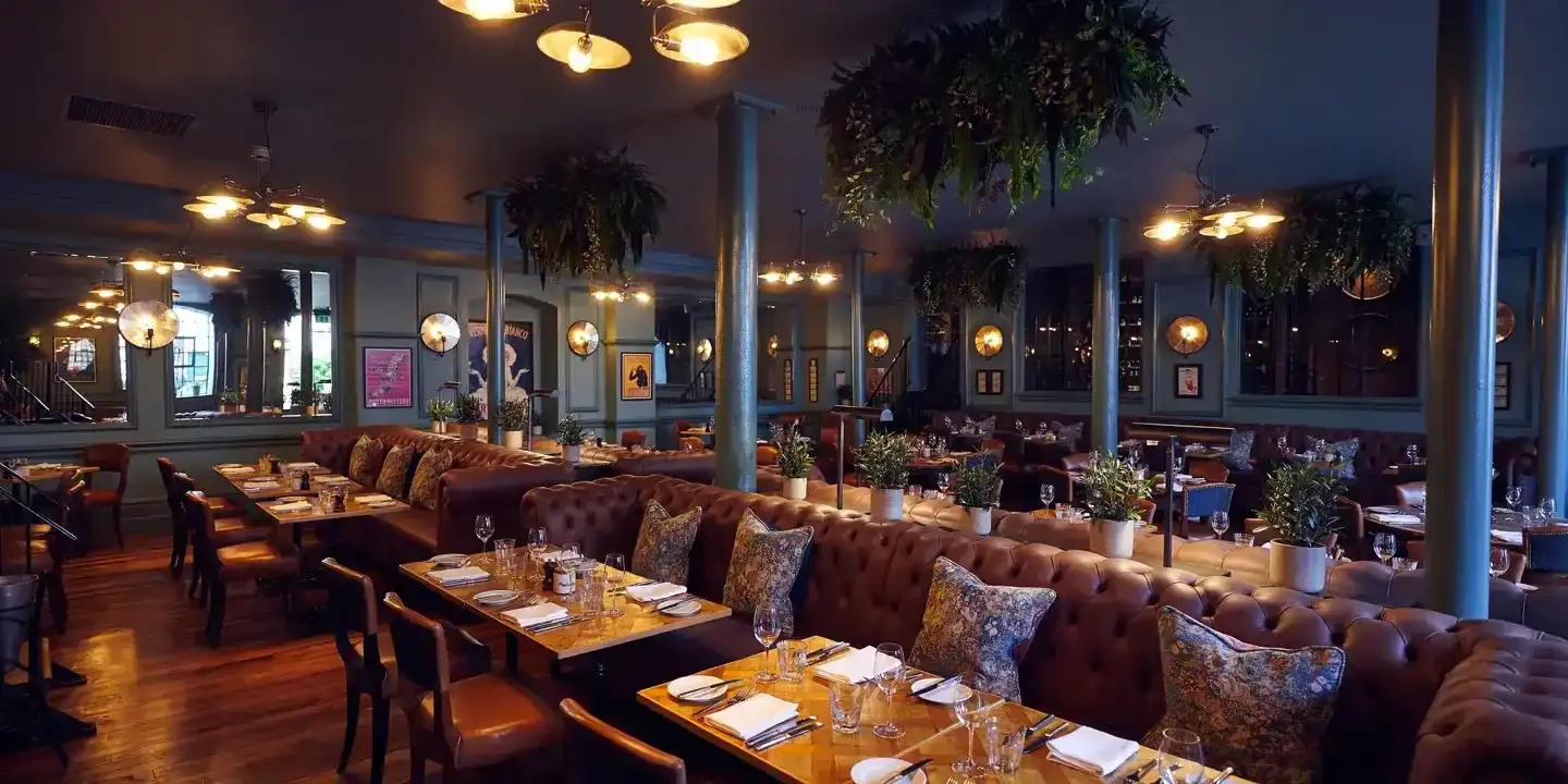 A spacious dining room filled with numerous tables, chairs and ceiling plants