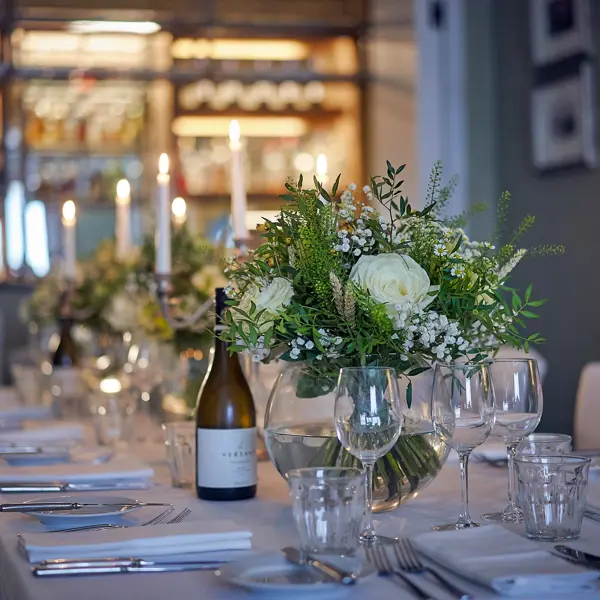 A beautifully arranged table for a formal dinner, complete with an elegant wine bottles, glasses and bouquets. 