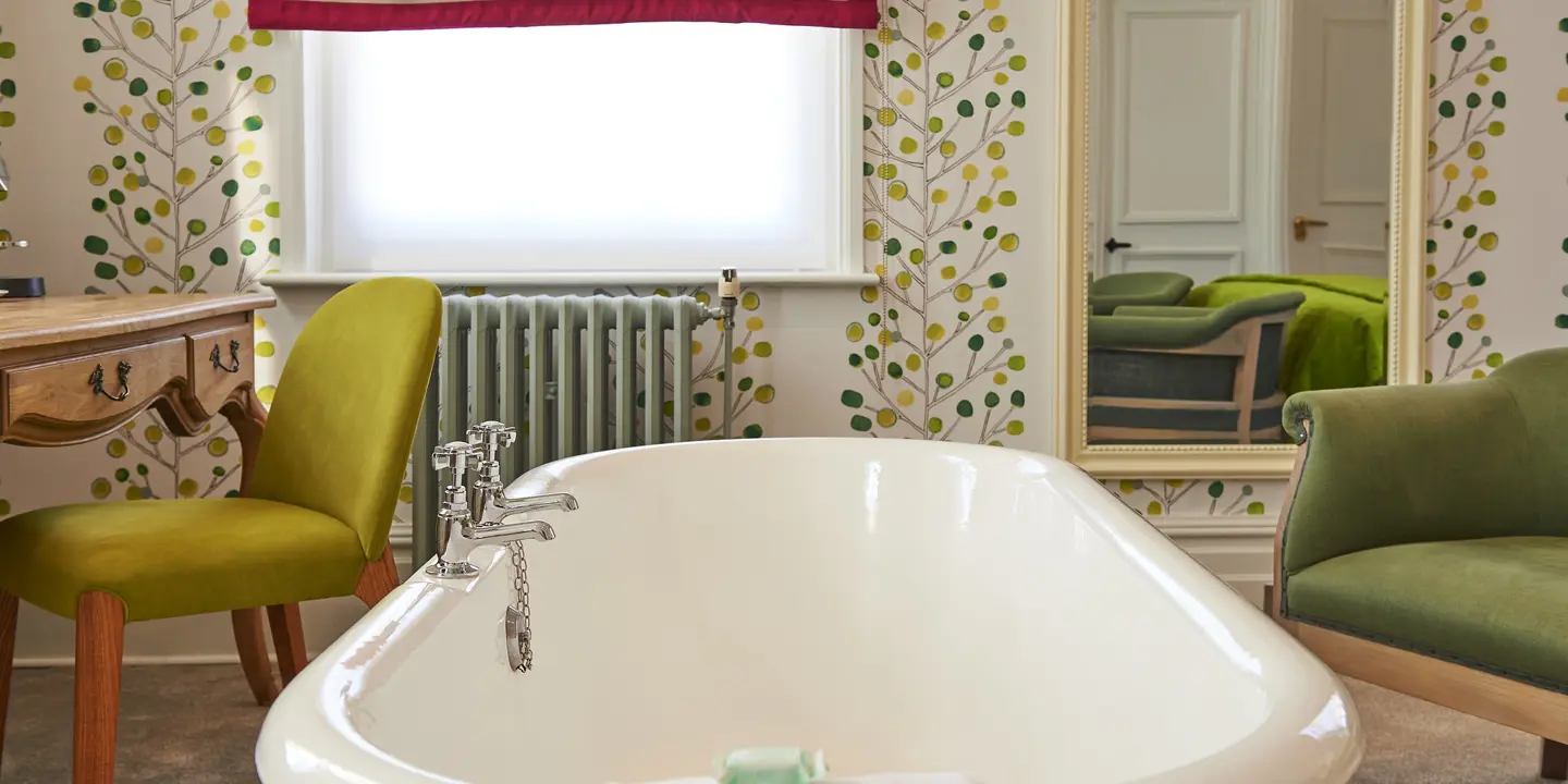 A room featuring a bathtub, chair, and mirror.