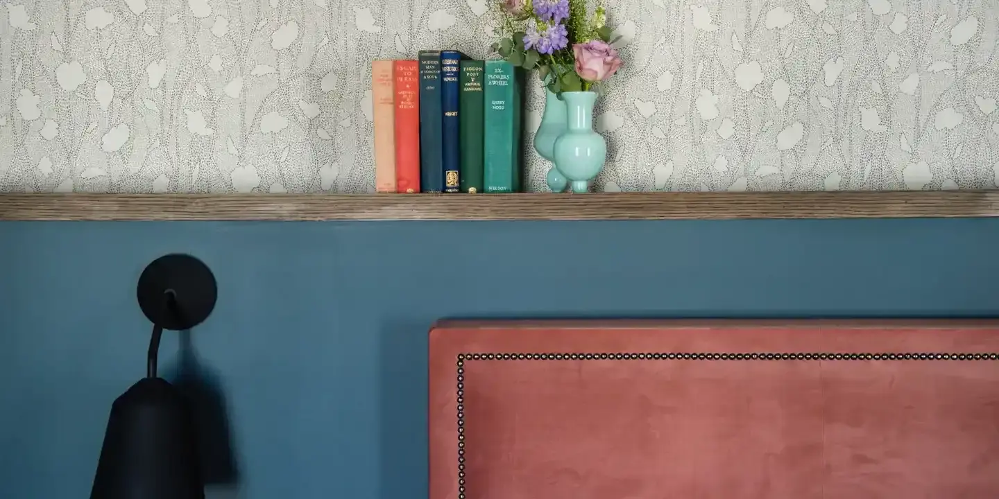 Bookshelf displaying a collection of books with a vase placed on top.
