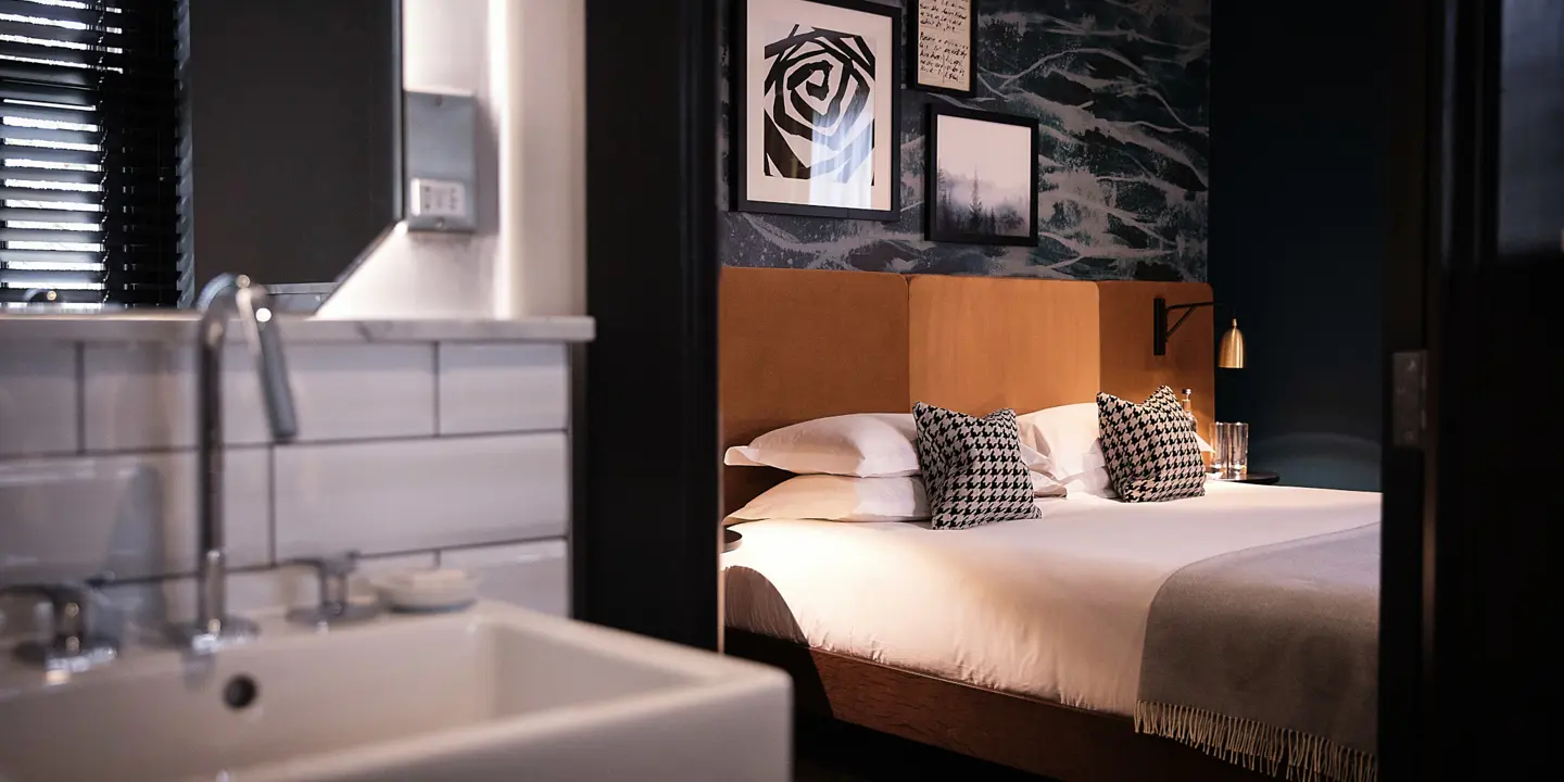 An elegantly furnished hotel room featuring a comfortable bed, a sleek sink, and a large window offering scenic views.