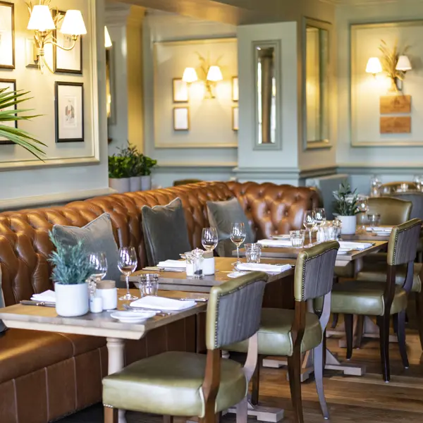 A spacious dining room filled with numerous tables and leather chairs.