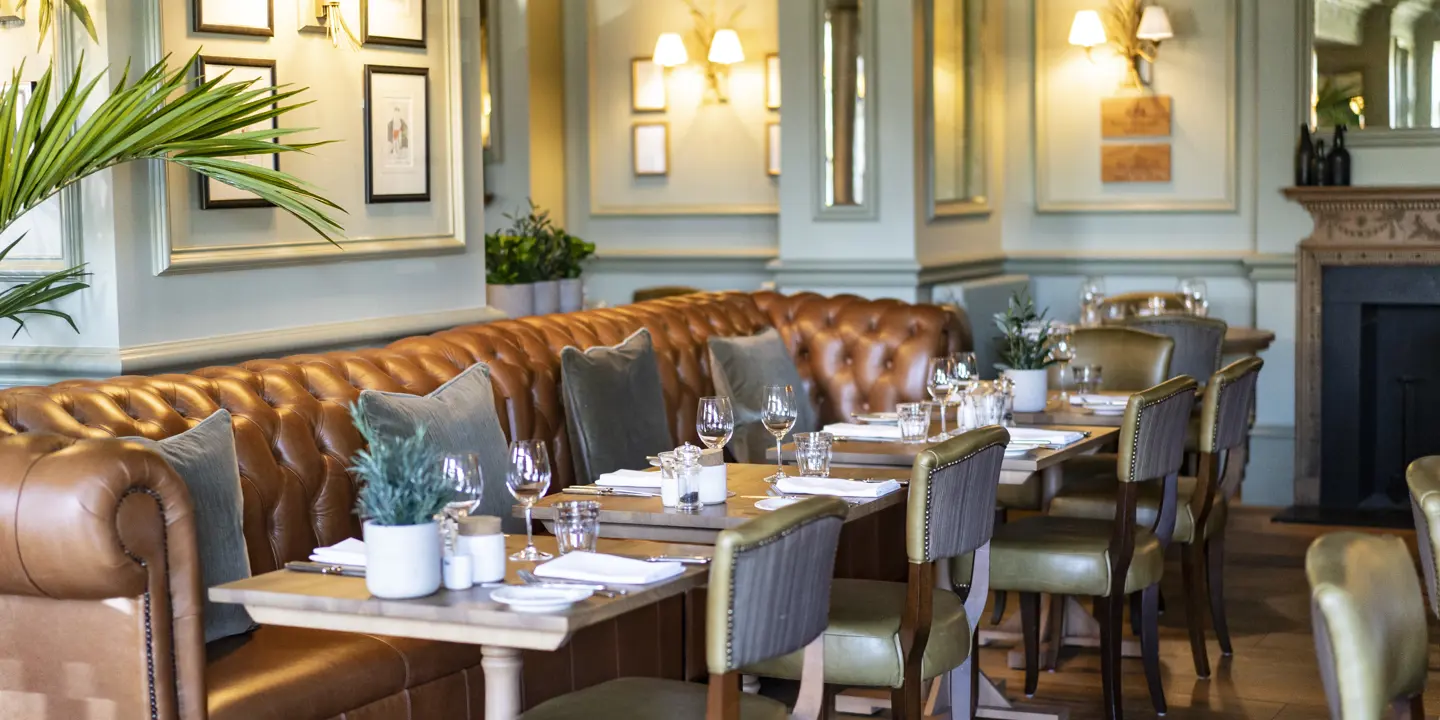 A spacious dining room filled with numerous tables and leather chairs.