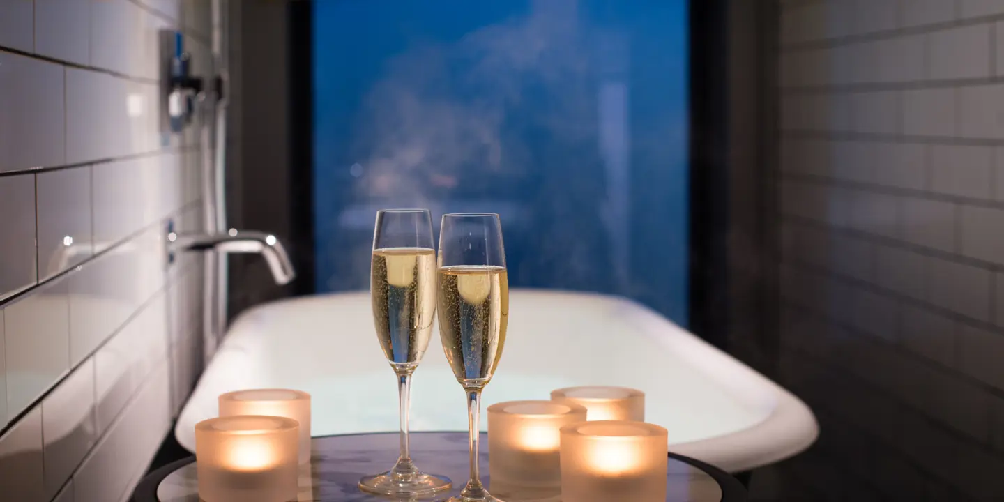 2 glasses of Champagne in front of a bath with candles.