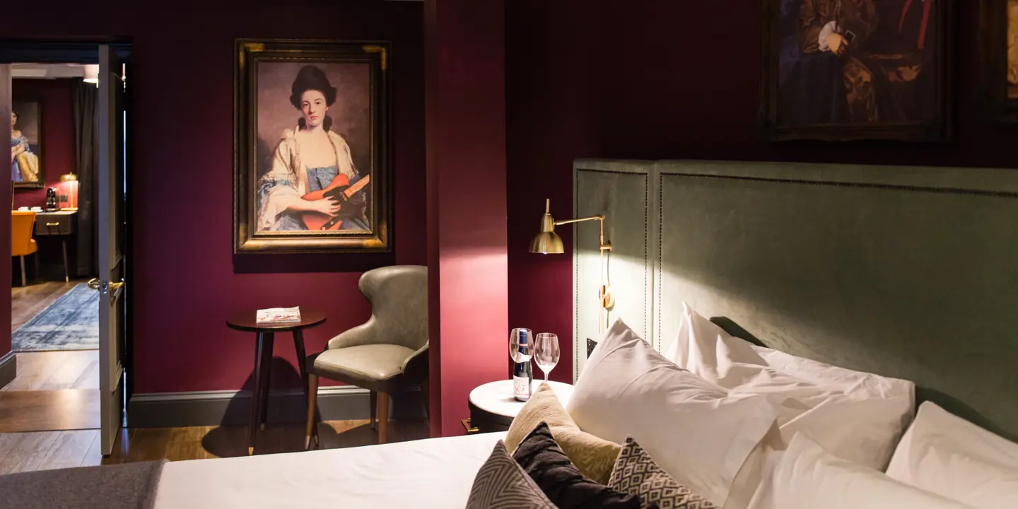 Hotel room featuring a comfortable bed, chairs, and wall paintings.