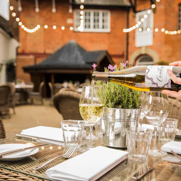 Outdoor dining table with a waiter pouring wine into a wine glass