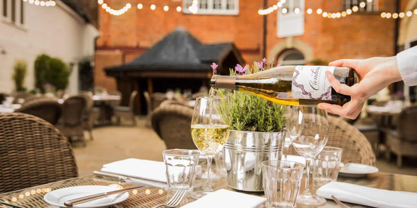 Outdoor dining table with a waiter pouring wine into a wine glass