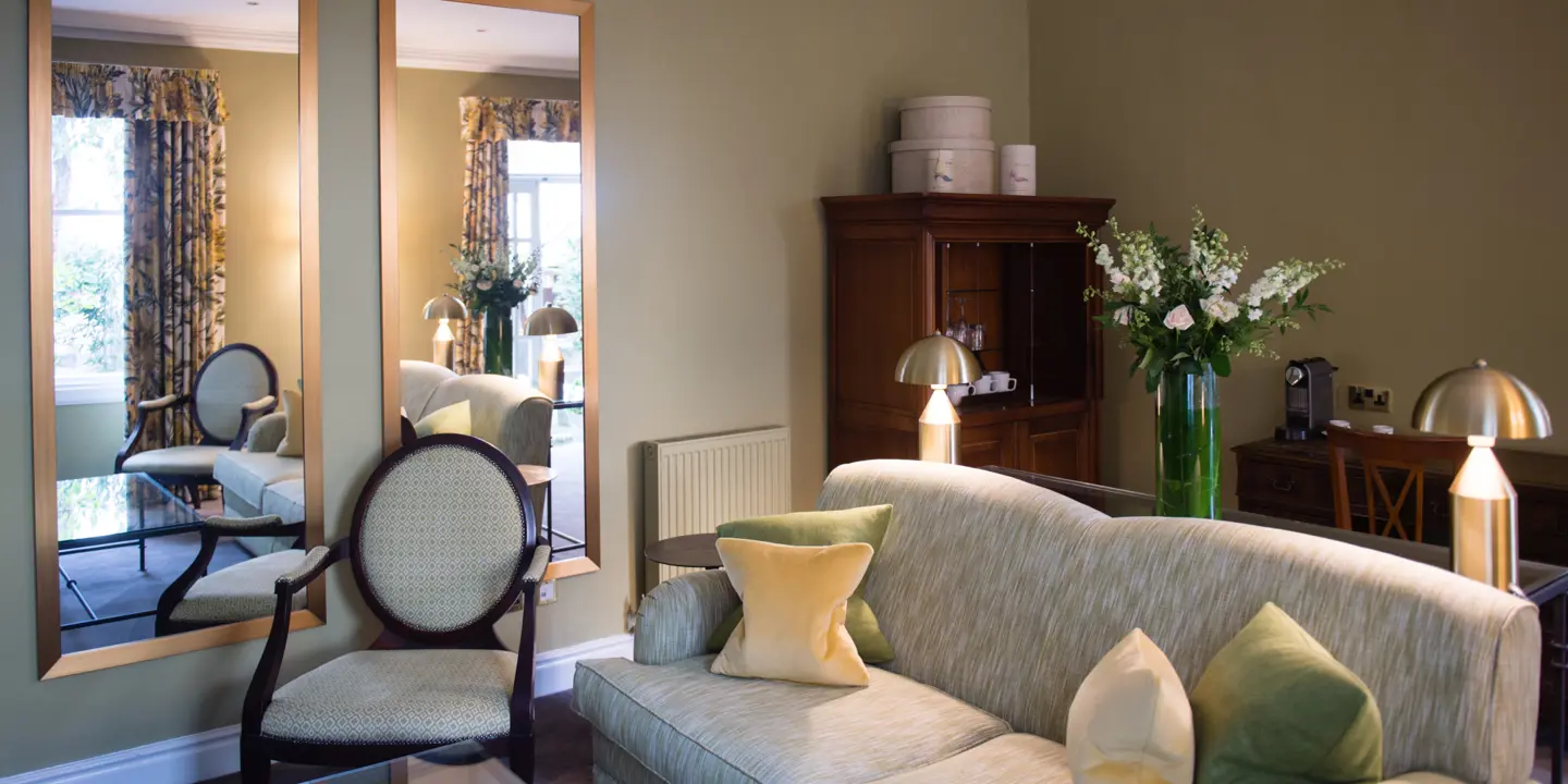 A well-furnished living room with an expansive mirror.