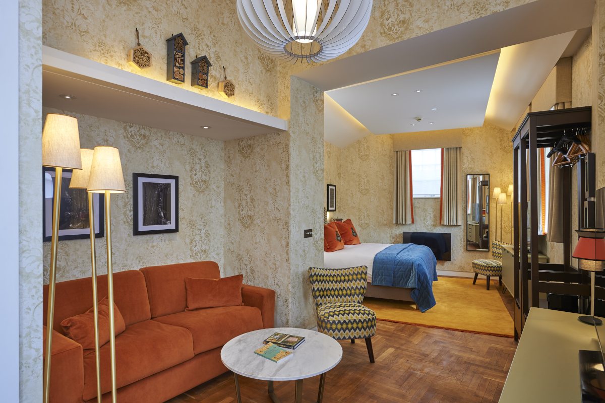 An elegantly furnished hotel room featuring a comfortable bed, sofa and a functional desk.