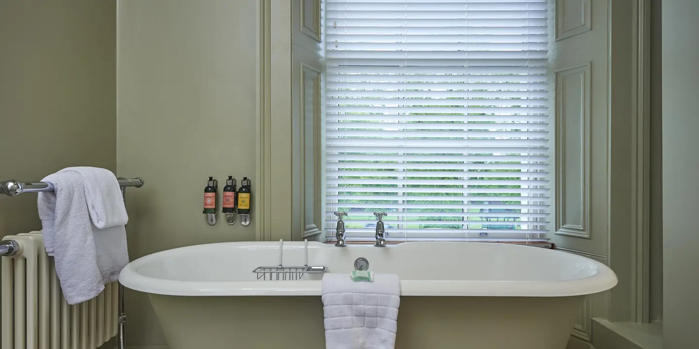 Large bath in the centre of the spacious room with ample light from the large window