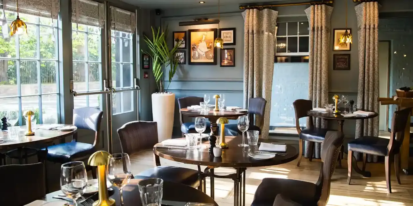 A restaurant featuring tables, chairs, and windows.