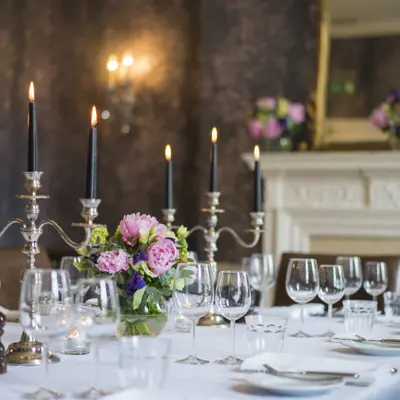 Table elegantly set for a formal dinner, adorned with candles and flowers.