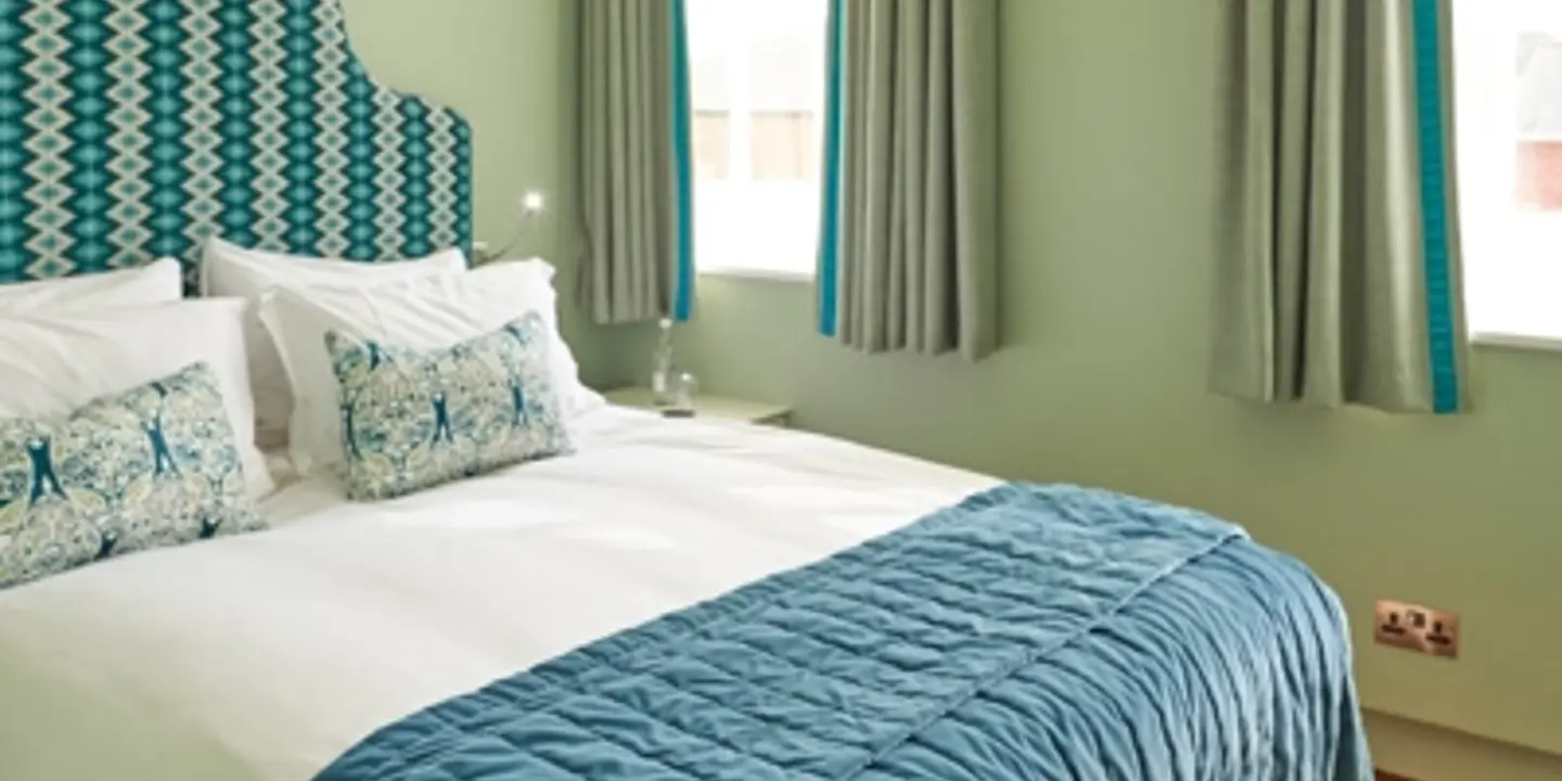 A bed adorned with a stylish blue and white comforter, accompanied by matching pillows.