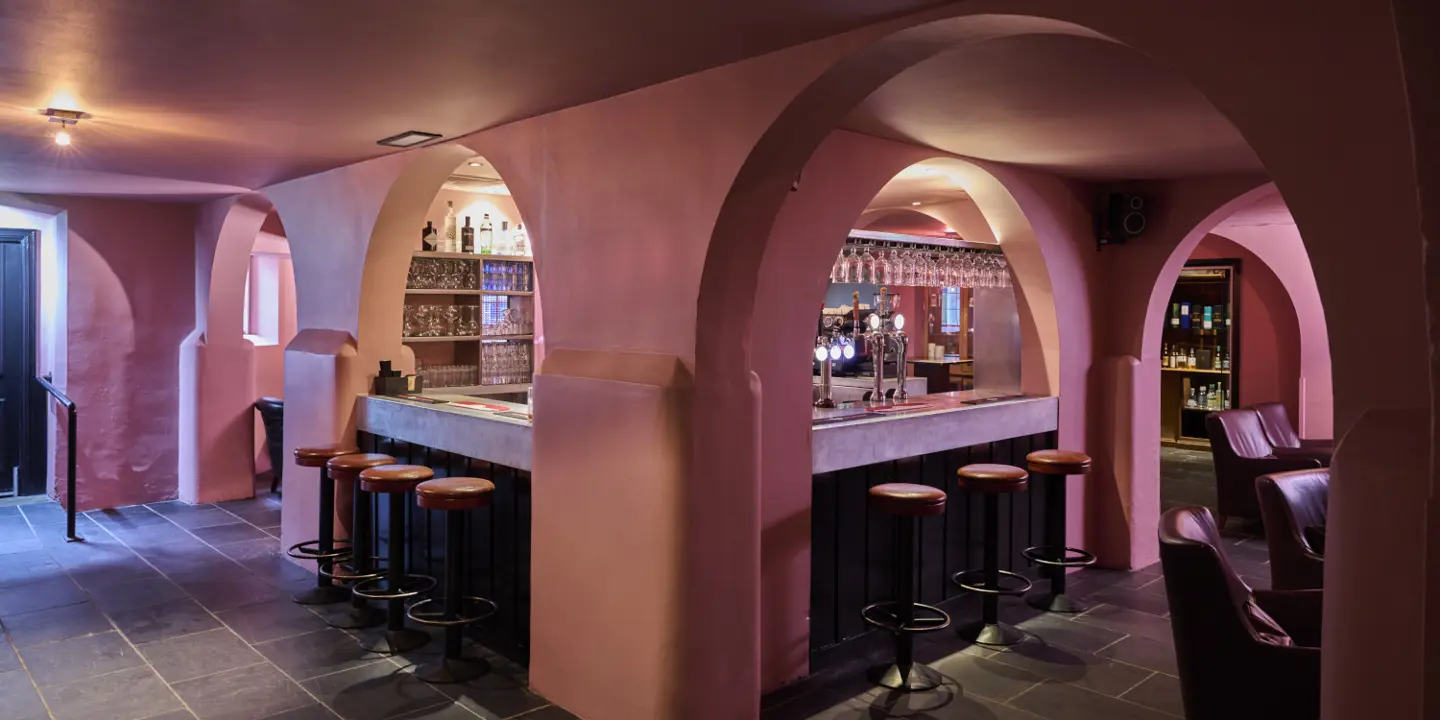 A bar with pink arches surrounding the interior with grey tiles as flooring