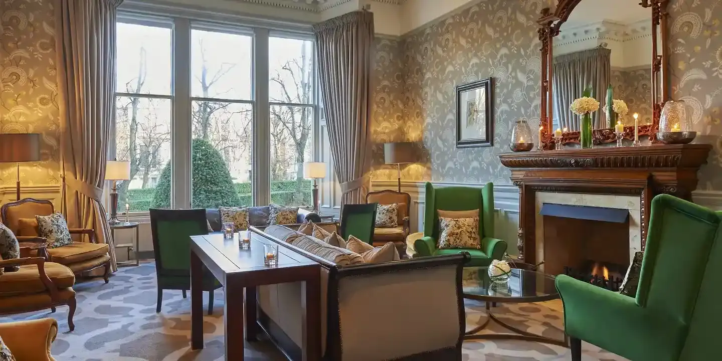 A well-furnished living room featuring a cosy fireplace and vibrant green chairs